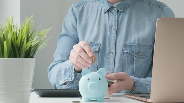 Woman putting money into piggy bank at table. Female saving money for household payments, utility bills, calculating monthly family budgets, making investments or strategy for personal savings