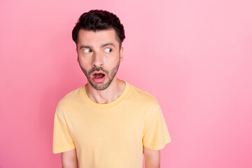 Portrait of interested curious man with stylish haircut wear yellow t-shirt staring at empty space isolated on pink color background