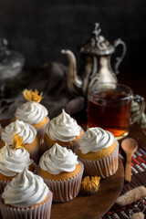 muffins or madeleines on a can and a wooden board with meringue and cream on top with an old teapot cup of tea and decorated with natural flowers