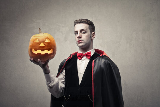 portrait of man disguised as Dracula with a halloween pumpkin in his hand