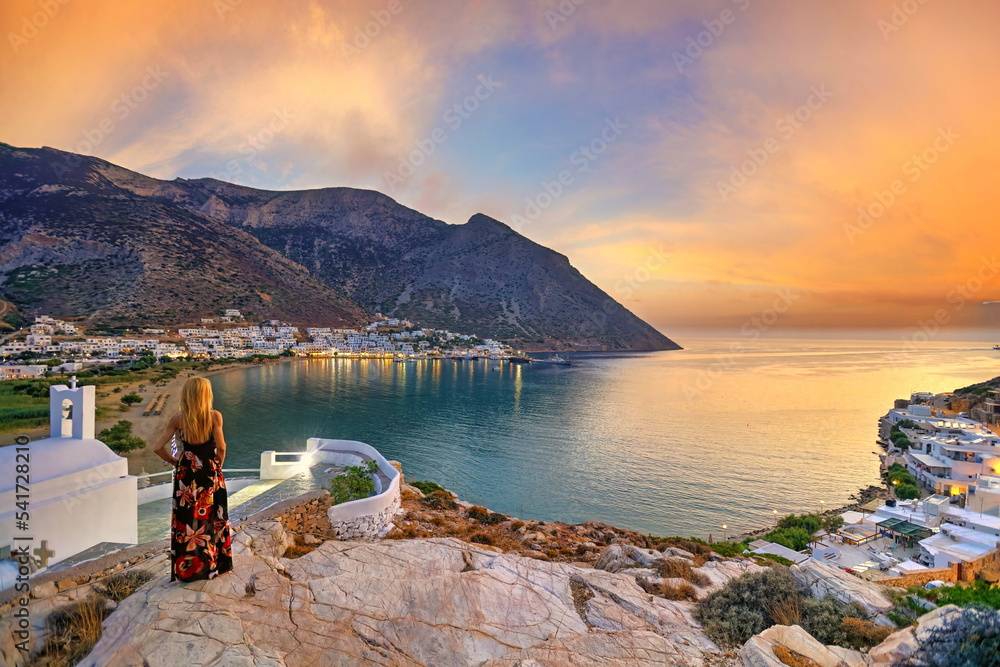 Wall mural a woman looking from agia marina at kamares beach of sifnos island at sunset, greece