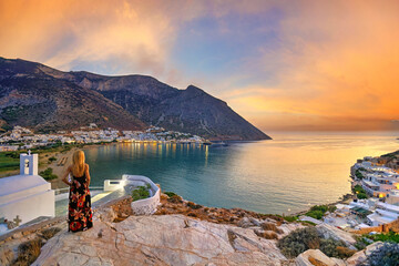 A woman looking from Agia Marina at Kamares beach of Sifnos island at sunset, Greece - obrazy, fototapety, plakaty