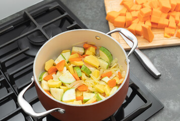 vegetable soup in pot on gas stove top. process of cooking vegan food. top view