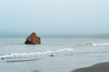 rusty shipwreck, the wreckage of a ship off the coast against the backdrop of a foggy sea