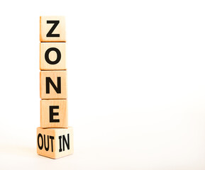 Zone in or out symbol. Concept words Zone in and Zone out on wooden cubes. Beautiful white table white background. Business zone in or out concept. Copy space.