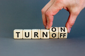 Turn on or off symbol. Concept words Turn off and Turn on on wooden cubes. Beautiful grey table grey background. Businessman hand. Business Turn on or off concept. Copy space.