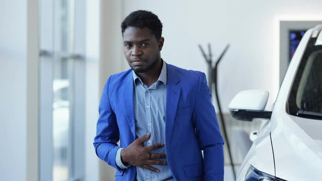 African American man explores automobile salon and searches nice car for reasonable price. Black customer wants to afford modern vehicle in luxury salon