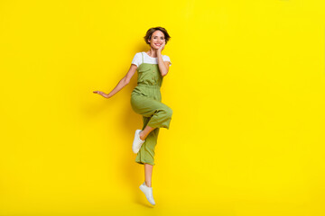 Fototapeta na wymiar Full length size photo of young stylish girl brown hair touch cheeks carefree weekend jump air relax nice outfit isolated on yellow color background