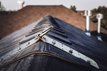 Selective focus on a metal temporary anchor installed on the peak of a roof for fall protection.  © Lost_in_the_Midwest