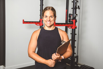 Portrait of a woman trainer using pad in weights room at fitness gym. Workout training in fitness gym.
