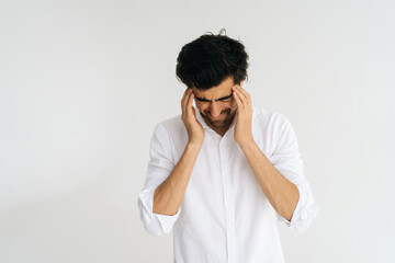 Studio portrait of depressed young man with closed eyes massaging temples suffering from headache painful, migraine, doubt make complicated decision standing on white isolated background.