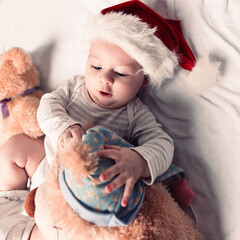 happy baby in Santa's hat with soft toys