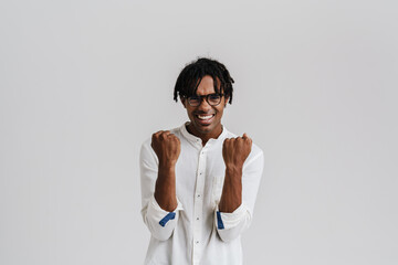 Excited young african man gesturing as winner while standing isolated