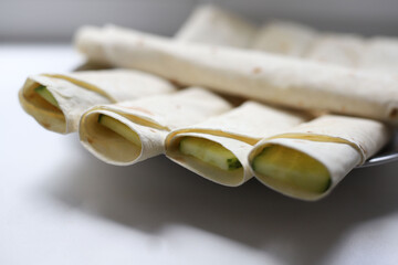 small pieces of lavash rolls with different
 stuffing lie round kitchen plate