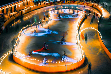 Ice rink in a snow-covered city park with New Year's illumination