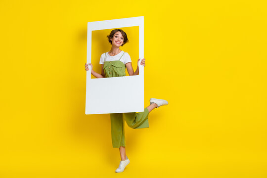 Full size cadre of young funny attractive cute popular blogger lady holding paper window showing satisfied face isolated on yellow color background