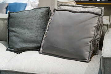 Close up light grey fabric sofa with warm cozy home interior background. Pillows on couch room decoration background