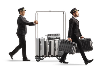 Bellboy carrying suitcases and other pushing suitcases on a hotel luggage cart