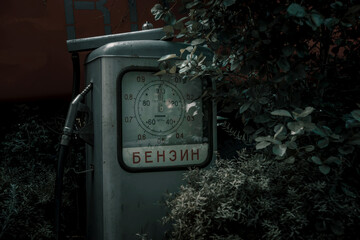 Old abandoned gas station. Shabby and rusty old column. Plants near an abandoned gas station.