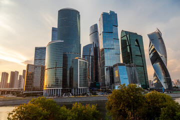 Beautiful high skyscrapers on the banks of the river. Sunset. Tall towers of glass and concrete. Beautiful city buildings.