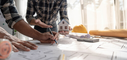 Obraz premium Concept architects, engineer holding pen pointing equipment architects On the desk with a blueprint in the office, Vintage, Sunset light.Selective Focus