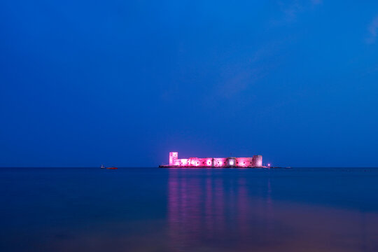 A castle in the middle of the sea, illuminated at night in the blue hour. Mersin kız kalesi