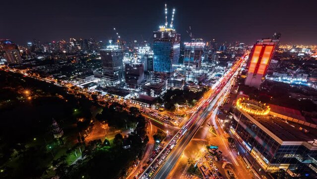Time-lapse of construction site at night, car traffic transportation on road in Asia city, high angle view. Advanced building technology, busy downtown cityscape, developing industrial country concept
