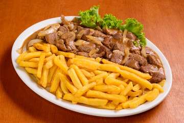 Filet mignon with fries, served Brazilian style on wooden table.