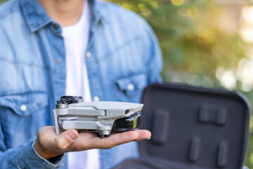 Selective focus close up view of a folded helicopter remote-controlled toy resting on the hands of an unrecognizable boy