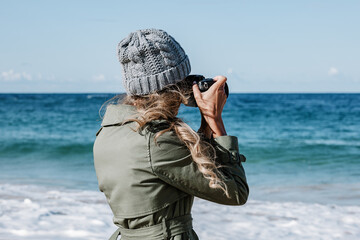 Young woman photographing seascape on beach
