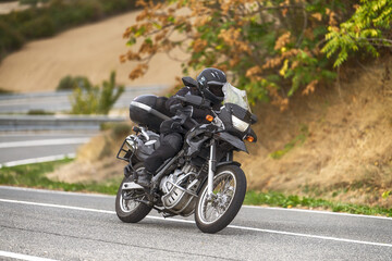 Motorcyclist riding on a curvy road with a large-displacement motorcycle.