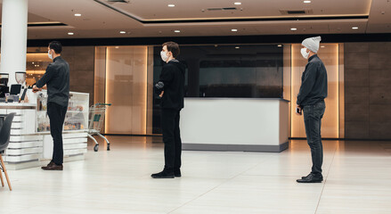 shoppers in protective masks standing in a queue in a supermarket