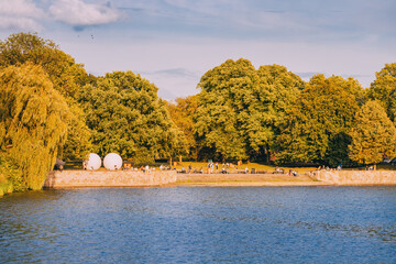 People resting in Munster city park and watching sunset over Aasee lake.