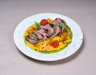Grilled meat with delicious yellow sauce. Cherry tomatoes.  Beautiful plate. Fresh tasty food in restaurant.