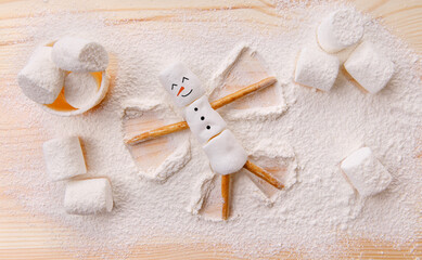 Christmas happy marshmallow man making an angel on the snow