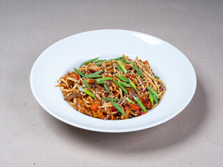 Asian cuisine. Close-up of a plate with wok noodles, sesame seeds and green onions.