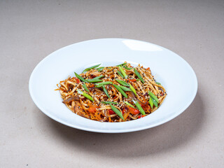Asian cuisine. Close-up of a plate with wok noodles, sesame seeds and green onions.