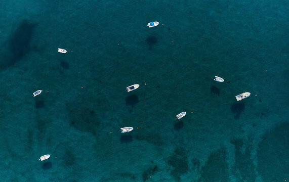 Aerial view of a group of speedboats surrounded by a transparent blue sea moored in Isca sullo Ionio, Calabria, Italy.