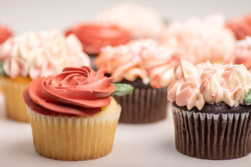 Variety of cupcakes on white table. Decorated with floral frosting design