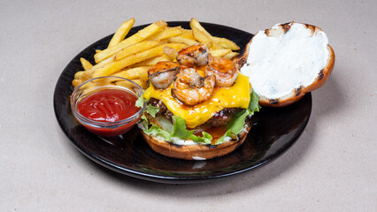 Delicious food in the restaurant. French fries, ketchup. Opened burger with cheese, fried shrimps, lettuce. Beautiful black plate.