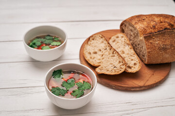 wholegrain bread and a bowl of soup on a wooden background.