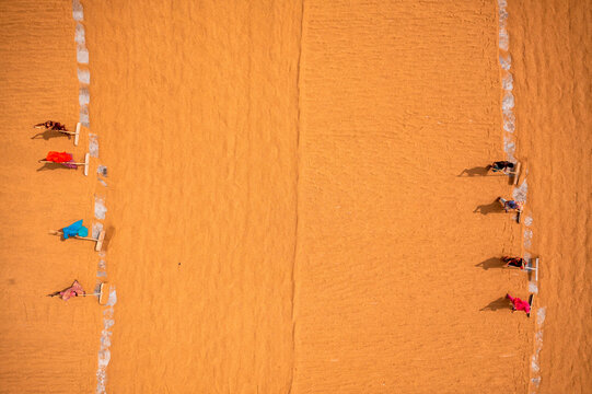 Aerial view of farmers working in a field drying rice on a rice field in Dhamrai, Dhaka, Bangladesh.