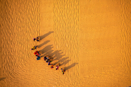 Aerial view of farmers working in a field drying rice on a rice field in Dhamrai, Dhaka, Bangladesh.