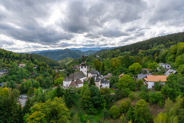 view of the village and Roman Catholic church in Spania Dolina with green summer forest - obrazy, fototapety, plakaty