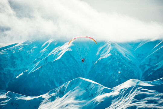 Gudauri ski resort panorama with tandem paragliders high in air in cold winter day with caucasus background