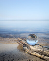 Butterfly on a glass ball on the beach reflecting the lake and sky. Concept of tranquility and zen. 