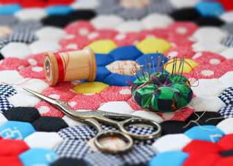 Quilting supplies on a colorful hexagon mosaic patterned quilt. The creative quilter. 