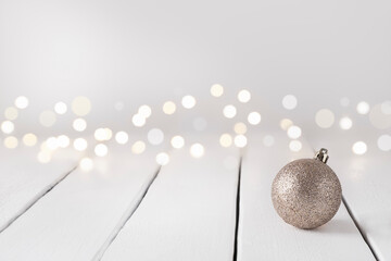 Festive background with Christmas ball and bokeh on white table, copy space