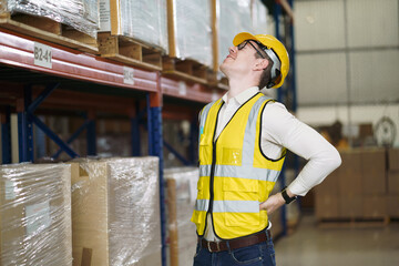 Back ache concept of factory worker. Young man looking painful expression. Portrait of young male feeling pain while touching shoulder and his back by hand. Man suffering from office syndrome.