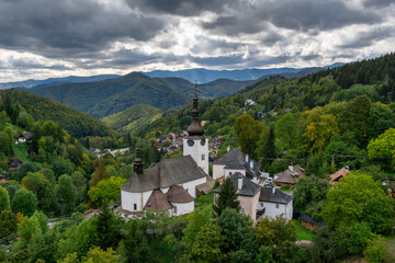 Fototapeta na wymiar view of the village and Roman Catholic church in Spania Dolina with green summer forest